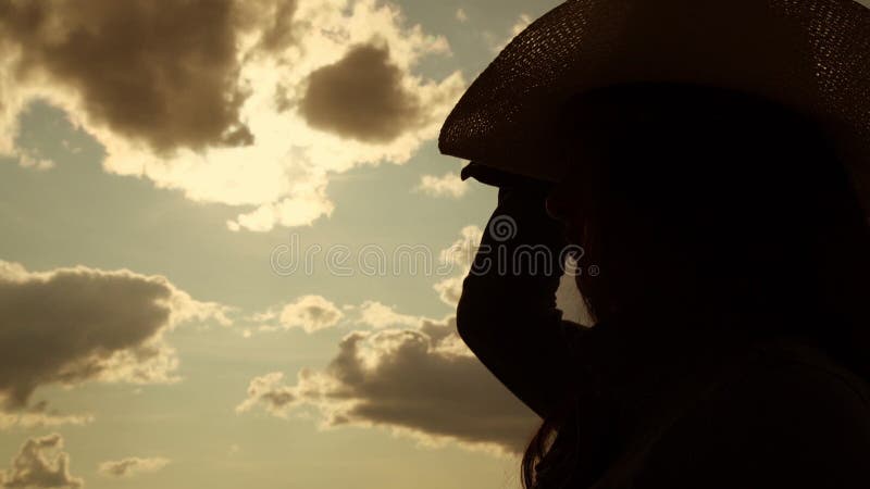 Long haired girl silhouette puts on cowboy hat close view