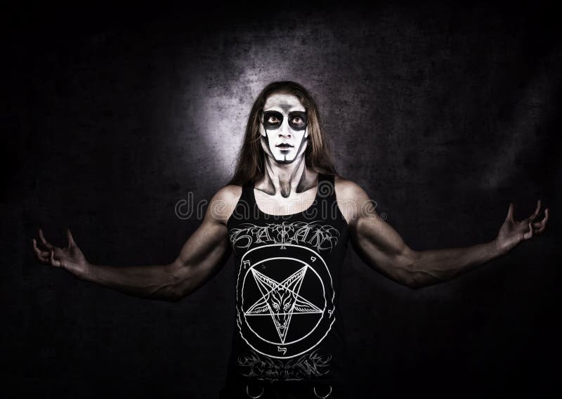 Long haired man in goth style clothes with Satan symbols.