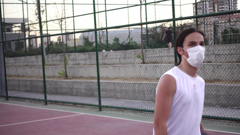 Long haired teenager dribbling and shooting the ball in basketball court