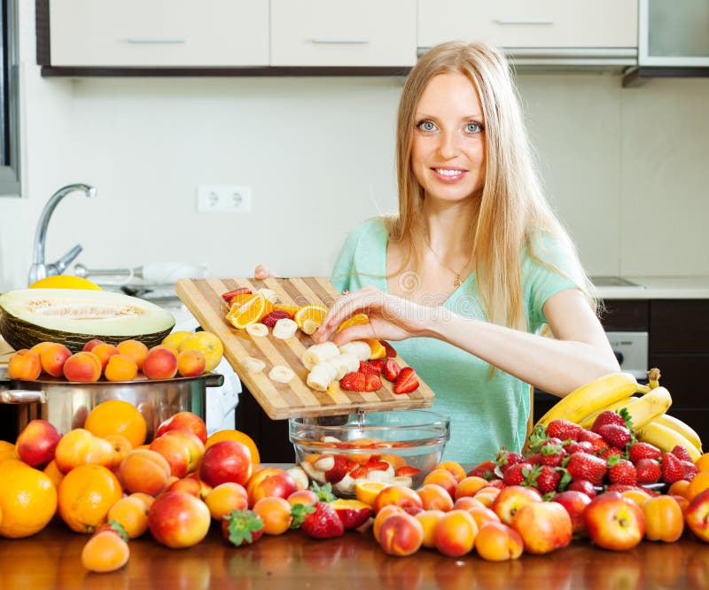 Long-haired woman cooking fruit salad stock image
