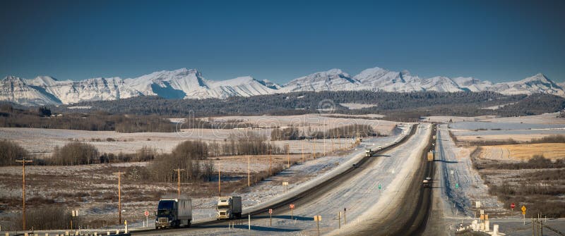 Long haul trucks driving in mountains on highway in winter