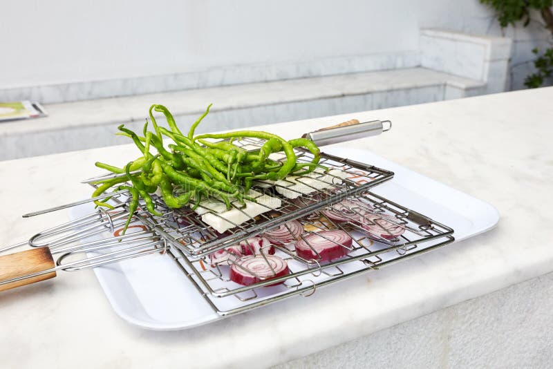 Longs poivrons verts frais, fromage blanc et oignons rouges coupés en tranches placés entre la grille de gril de fil sur un plate photo stock Longs poivrons verts frais, fromage blanc et oignons rouges coupés en tranches placés entre la grille de gril de fil sur un plate photo stock
