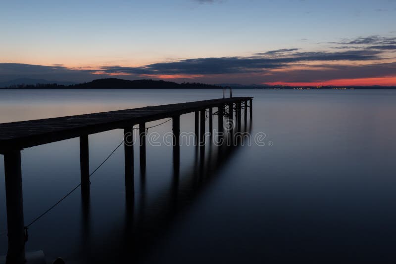 Longue vue d'exposition d'un pilier sur un lac au crépuscule, avec le col éloigné. Longue vue d'exposition d'un pilier sur un lac au crépuscule, avec de l'eau les nuages et parfaitement toujours colorés éloignés