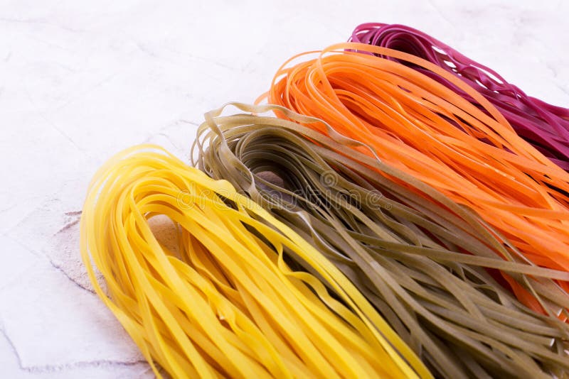 Longues pâtes colorées sur le fond beige photographie stock libre de droits Longues pâtes colorées sur le fond beige photographie stock libre de droits