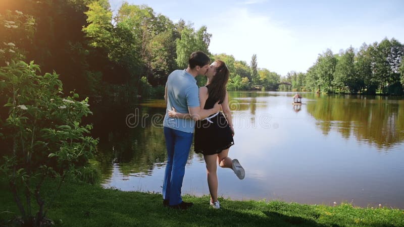Longueur de mouvement lent de beaux jeunes couples embrassant par la rivière à la forêt