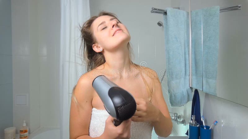 Longueur de mouvement lent des cheveux de séchage de belle jeune femme ayant ensuite la douche