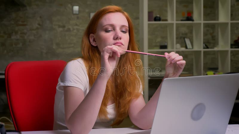 Longueur de se reposer caucasien ennuyé de femme de gingembre d'intérieur sur son lieu de travail près de l'ordinateur portable banque de vidéos