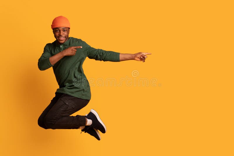 Look At This. Cherful african guy pointing aside while jumping in air