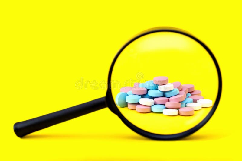 A look through a magnifying glass at a pile of pills on a yellow background. Search the ingredients of medicines, vitamins