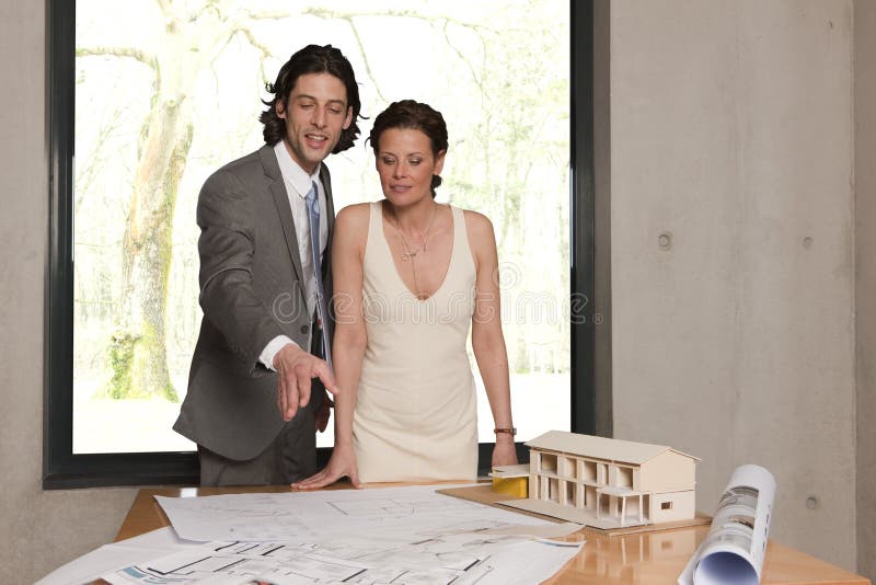 Young man showing his wife the plans for their new home. Young man showing his wife the plans for their new home