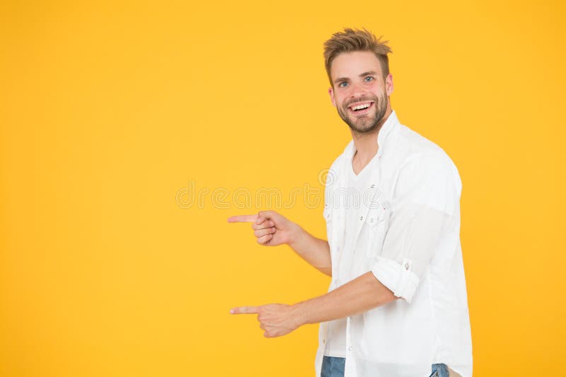 Look there. Man pointing at copy space. Check this out. Man muscular handsome smiling unshaven guy on yellow background stock image Look there. Man pointing at copy space. Check this out. Man muscular handsome smiling unshaven guy on yellow background stock image