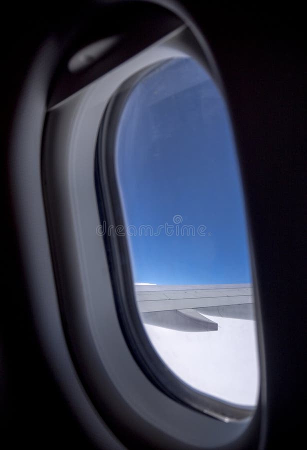 Looking at airplane wing through the window with blue sky during flight. stock photos Looking at airplane wing through the window with blue sky during flight. stock photos