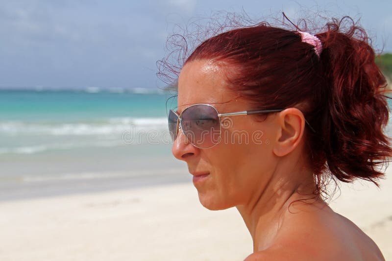 Ryšavý zrelý žena pozerá na more na karibský.