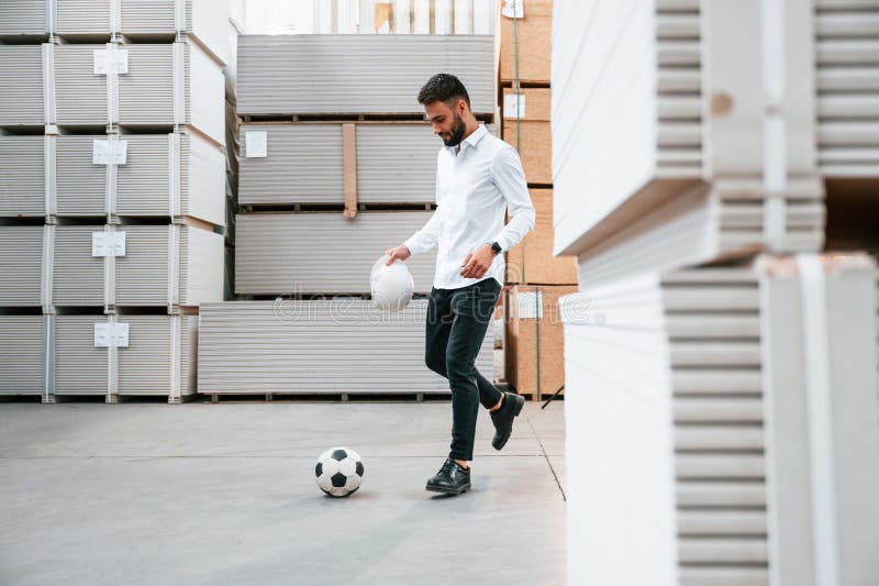Looking at Soccer Ball. Storage Worker is in the Warehouse with Bunch