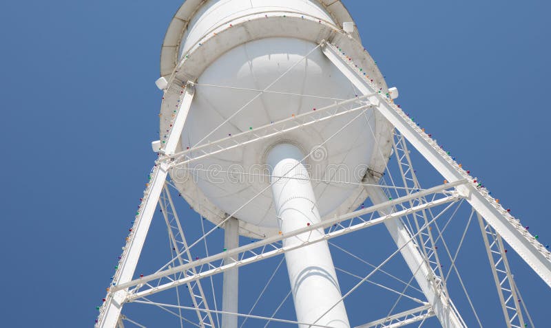 A bright white water tower from below with a bright blue sky.