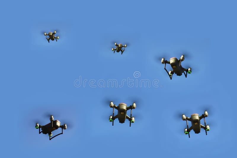 Looking up at multiple small red and black drones flying against a blue sky background stock photos