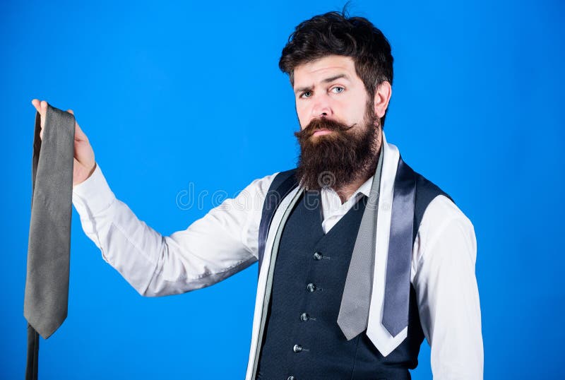 It looks superbly stylish. Bearded man holding stylish necktie. Brutal guy in stylish clothes choosing classy accessory. Fashion model in trendy hipster style. Stylish businessman.