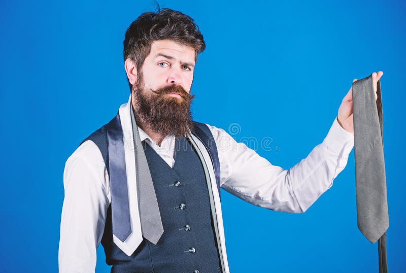 It looks superbly stylish. Bearded man holding stylish necktie. Brutal guy in stylish clothes choosing classy accessory. Fashion model in trendy hipster style. Stylish businessman.