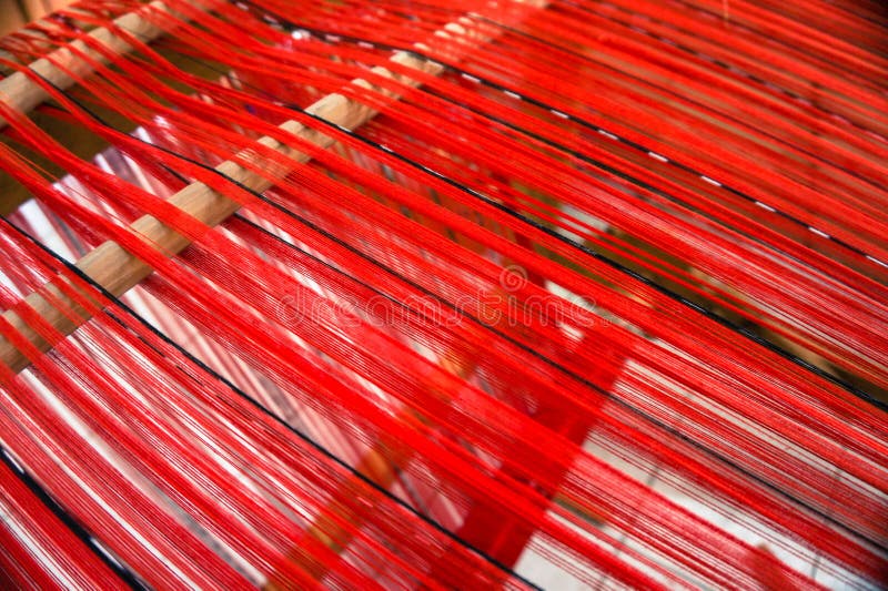 Loom strung with red threads for weaving