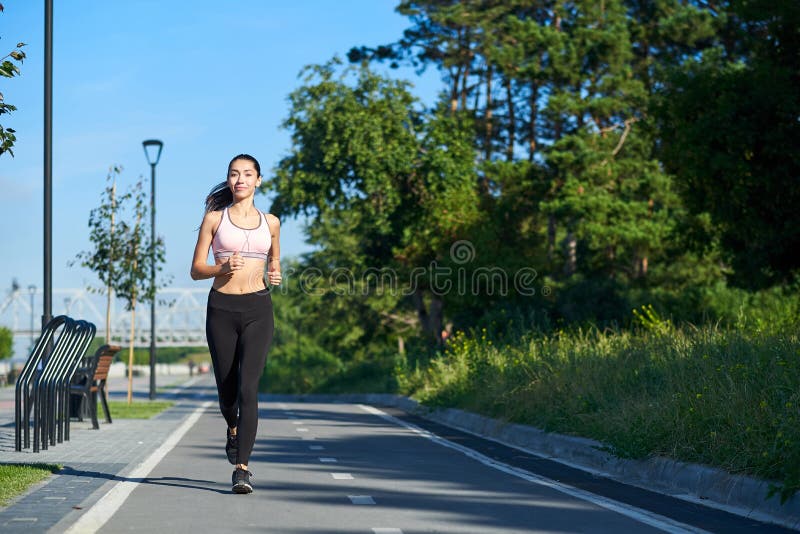 Lopende Vrouw op renbaan tijdens opleidingssessie Het vrouwelijke agent praktizeren op het spoor van het atletiekras stock foto Lopende Vrouw op renbaan tijdens opleidingssessie Het vrouwelijke agent praktizeren op het spoor van het atletiekras stock foto