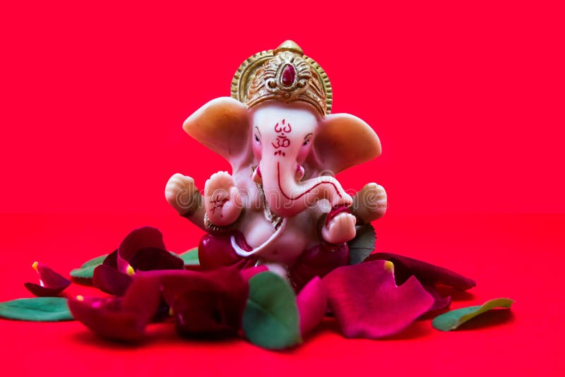 Lord Ganesha Idol with Rose Petals on Red Background, Ganesha Chautrhi ...