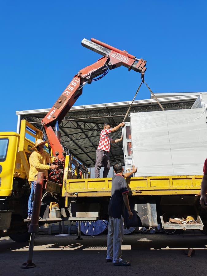Lorry Crane Loading Switchboard with Workers during Sunny Day Editorial