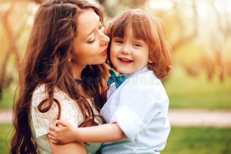 los abrazos de la mamá y el niño felices del beso embroman al hijo al aire libre en primavera o verano imagen de archivo los abrazos de la mamá y el niño felices del beso embroman al hijo al aire libre en primavera o verano imagen de archivo