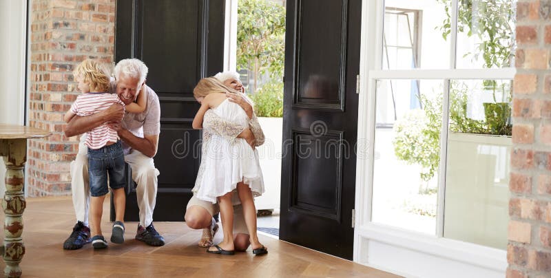 Los abuelos que visitan doblan y se arrodillan para abrazar a nietos foto de archivo libre de regalías Los abuelos que visitan doblan y se arrodillan para abrazar a nietos foto de archivo libre de regalías
