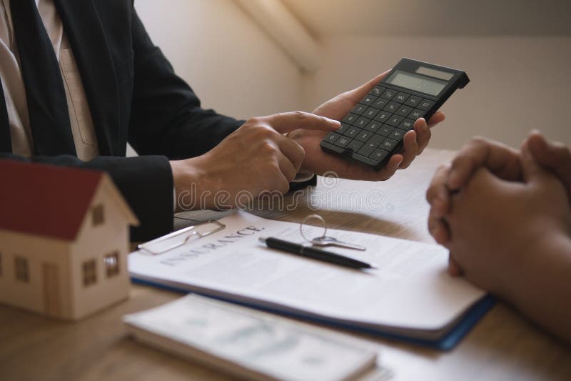 Los agentes calculan el tipo de pago del préstamo o el importe de las primas de seguro para los clientes que se ponen en contacto fotografía de archivo Los agentes calculan el tipo de pago del préstamo o el importe de las primas de seguro para los clientes que se ponen en contacto fotografía de archivo