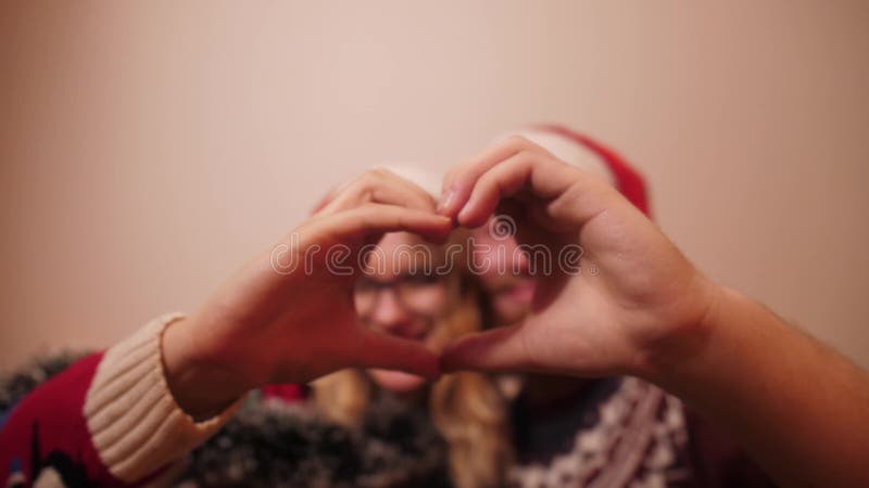 Los amantes de la navidad muestran un corazón con sus manos metrajes