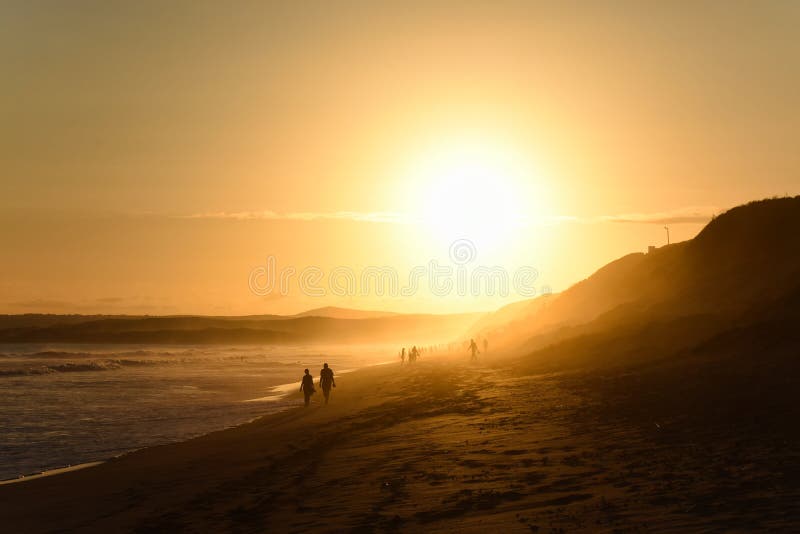 Los ancianos juntan caminar en la playa de la puesta del sol de la tarde imagenes de archivo Los ancianos juntan caminar en la playa de la puesta del sol de la tarde imagenes de archivo