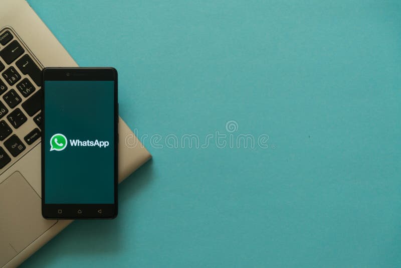 Whatsapp logo on smartphone placed on laptop keyboard.