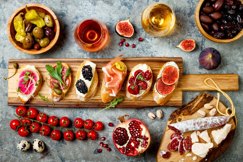 Los aperitivos presentan con bocados y vino italianos de los antipasti en vidrios Brushetta o tapas españoles tradicionales autén imagenes de archivo Los aperitivos presentan con bocados y vino italianos de los antipasti en vidrios Brushetta o tapas españoles tradicionales autén imagenes de archivo