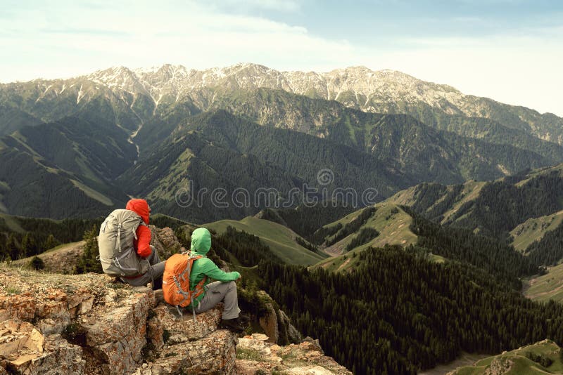 Los backpackers de las mujeres disfrutan de la opinión sobre el acantilado del pico de montaña imagenes de archivo Los backpackers de las mujeres disfrutan de la opinión sobre el acantilado del pico de montaña imagenes de archivo