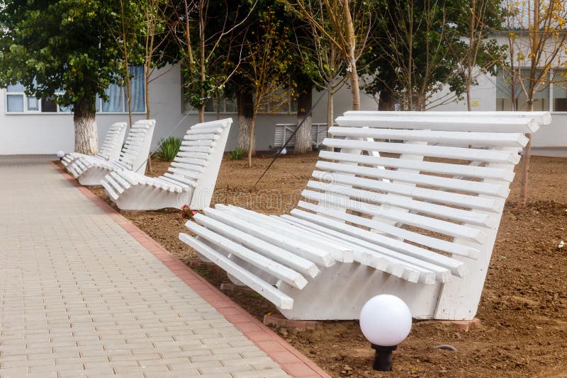 Los bancos vacíos de madera blancos en la ciudad parquean imágenes de archivo libres de regalías Los bancos vacíos de madera blancos en la ciudad parquean imágenes de archivo libres de regalías