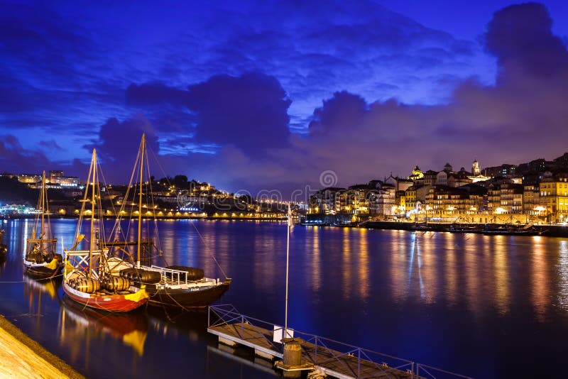 Los barcos amarraron a lo largo de la orilla del río con las luces que reflejaban en el río del Duero en Oporto, Portugal