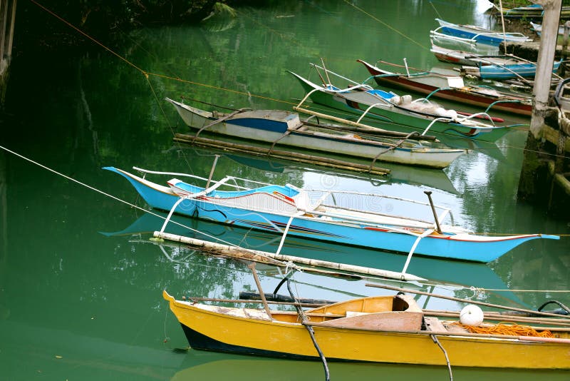 Los barcos de pesca filipinos tradicionales se colocan en la bahía cerca de la costa imágenes de archivo libres de regalías Los barcos de pesca filipinos tradicionales se colocan en la bahía cerca de la costa imágenes de archivo libres de regalías