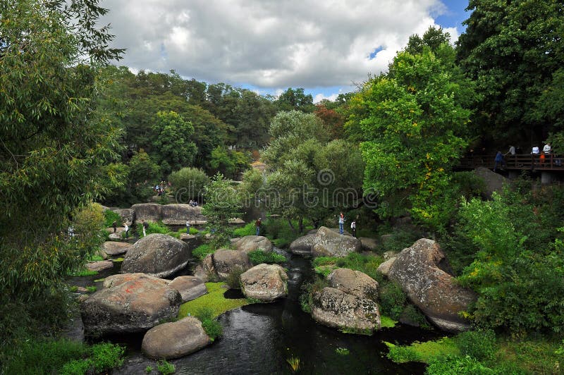 Los cantos rodados enormes mienten en el río entre altos árboles verdes contra el cielo azul foto de archivo libre de regalías Los cantos rodados enormes mienten en el río entre altos árboles verdes contra el cielo azul foto de archivo libre de regalías
