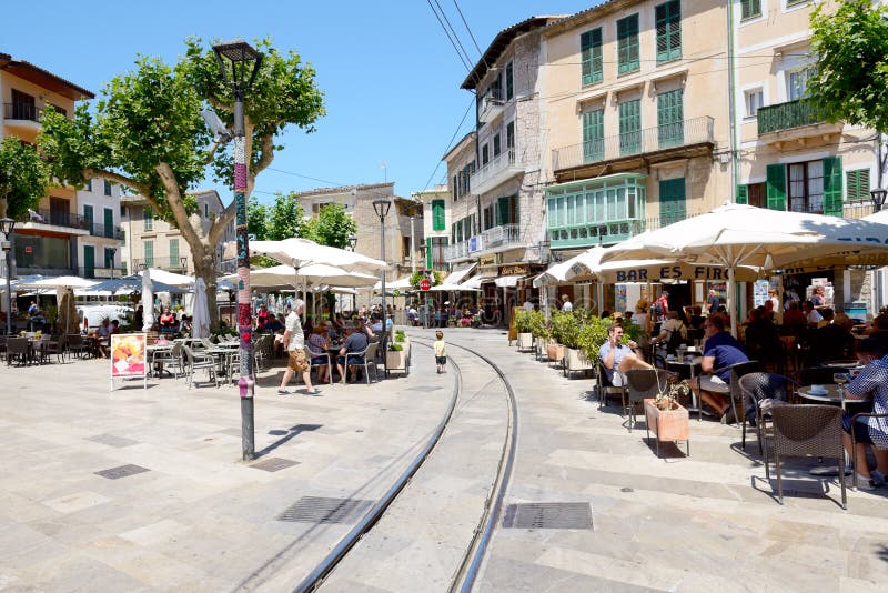 MALLORCA, SPAIN - JUNE 2: The tram rails are on street of Soller town and tourists are in outdoor restaurant on June 2, 2015 in Mallorca, Spain. Up to 60 mln tourists is expected to visit Spain in year 2015. MALLORCA, SPAIN - JUNE 2: The tram rails are on street of Soller town and tourists are in outdoor restaurant on June 2, 2015 in Mallorca, Spain. Up to 60 mln tourists is expected to visit Spain in year 2015.