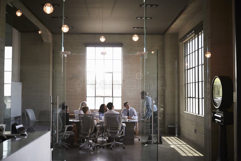 Los colegas del negocio en una reunión en un vidrio emparedaron la sala de reunión fotos de archivo libres de regalías Los colegas del negocio en una reunión en un vidrio emparedaron la sala de reunión fotos de archivo libres de regalías