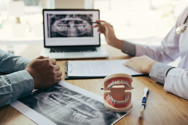 Dentists are discussing dental problems at report x-ray image on laptop screen to patients. Dentists are discussing dental problems at report x-ray image on laptop screen to patients.