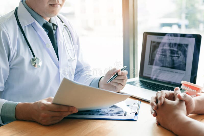 Asian young dentists are explaining about the dental root treatment of patients in the office. Asian young dentists are explaining about the dental root treatment of patients in the office.