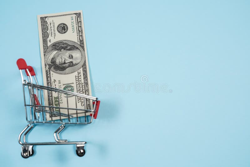 Los dólares de EE. UU. en carro de la compra sobre el fondo azul, billete de dólar recogen en el carro de la compra Concepto de d imagen de archivo libre de regalías Los dólares de EE. UU. en carro de la compra sobre el fondo azul, billete de dólar recogen en el carro de la compra Concepto de d imagen de archivo libre de regalías