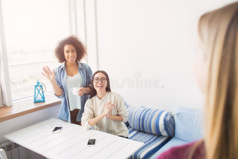 Los estudiantes han visto a su amigo Son felices sobre ése La muchacha afroamericana es permanente y que agita mientras que la mu fotos de archivo Los estudiantes han visto a su amigo Son felices sobre ése La muchacha afroamericana es permanente y que agita mientras que la mu fotos de archivo
