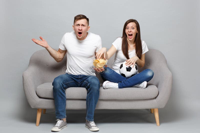 Los fanáticos del fútbol perplejos del hombre de la mujer de los pares animan para arriba el equipo preferido de la ayuda con el imagen de archivo libre de regalías Los fanáticos del fútbol perplejos del hombre de la mujer de los pares animan para arriba el equipo preferido de la ayuda con el imagen de archivo libre de regalías