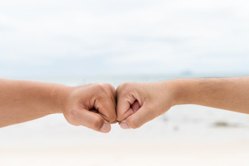 Los Hombres Dan El Puño Que Topa Juntos En El Mar Y El Cielo Borrosos