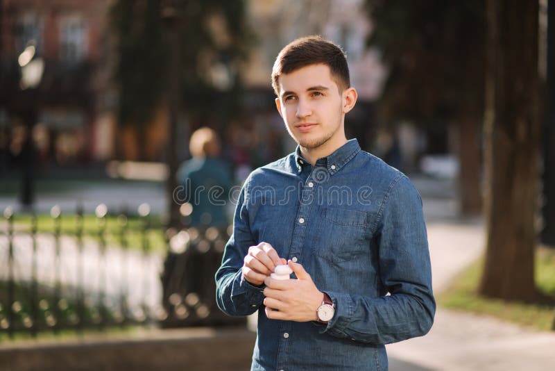 Los hombres jóvenes de negocios sacan unos auriculares inalámbricos y los ponen en los oídos El hombre escuchará al audiobool mie foto de archivo libre de regalías Los hombres jóvenes de negocios sacan unos auriculares inalámbricos y los ponen en los oídos El hombre escuchará al audiobool mie foto de archivo libre de regalías