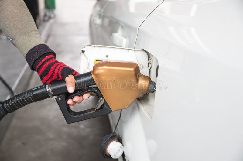 Los hombres sostienen el surtidor de gasolina para añadir el combustible en coche en la estación de servicio fotografía de archivo Los hombres sostienen el surtidor de gasolina para añadir el combustible en coche en la estación de servicio fotografía de archivo