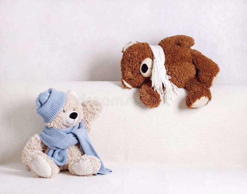 Los Juguetes De Peluche Para Niños Están Sentados En Un Sofá Blanco Con Una Bufanda De Punto Blanca Y Azul Y Sombrero Imagen de archivo - Imagen de sombrero, sofá: 159368869