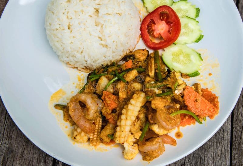Los mariscos frieron con la zanahoria, tomate cerca cortado del ajo, pepino con el arroz preparado en la placa blanca fotos de archivo libres de regalías Los mariscos frieron con la zanahoria, tomate cerca cortado del ajo, pepino con el arroz preparado en la placa blanca fotos de archivo libres de regalías